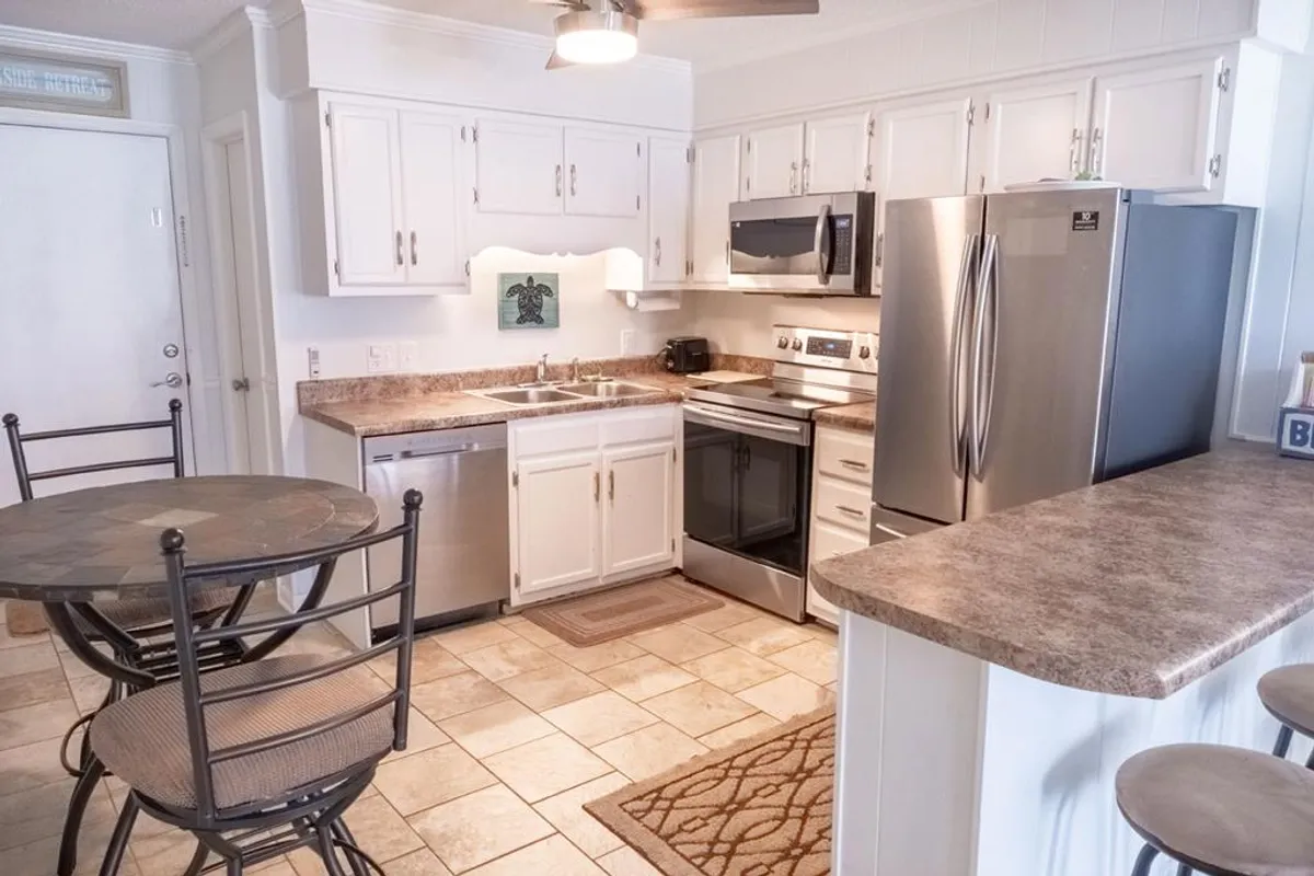 A well-appointed kitchen area with a spacious countertop, stainless steel appliances, bar stools for casual dining, and a dining table set for meals. The space is functional and open, ideal for both preparing and sharing meals as a group.