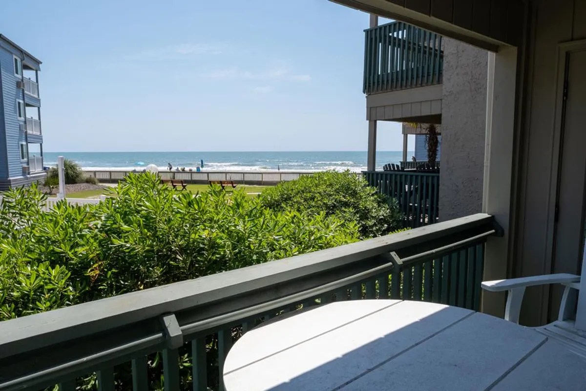 A tranquil balcony view with a patio table, lush green foliage, and expansive sea views. The setup invites relaxation, whether for morning coffee, sunset cocktails, or simply soaking in the ocean breeze and Myrtle Beach scenery.